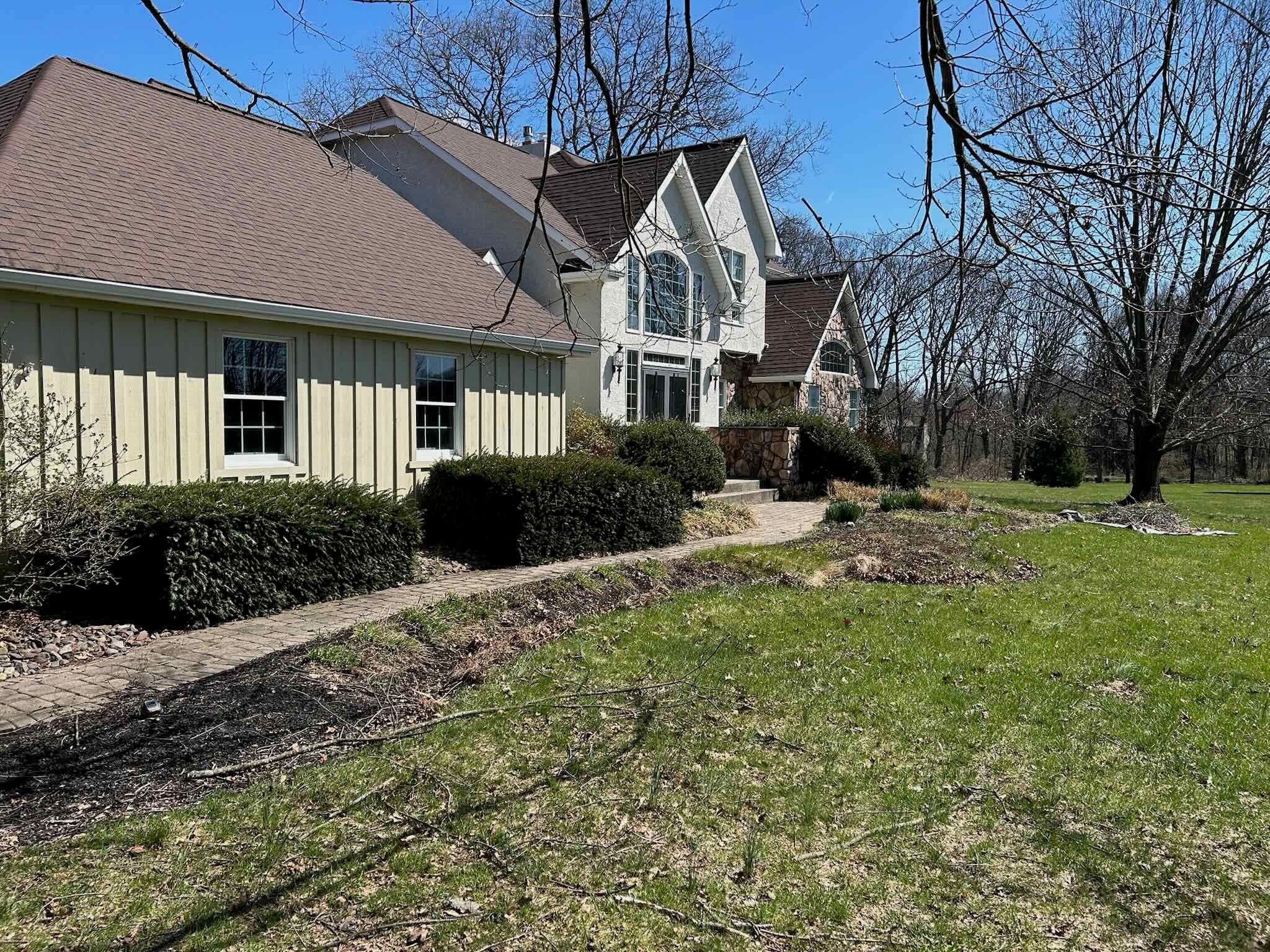 Front walkway beds before mulching, with thin old mulch, debris, and soft edges